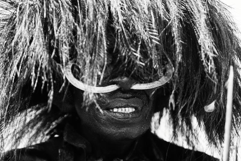 portrait of tribal warrior with feather wig and tusk nose piercing