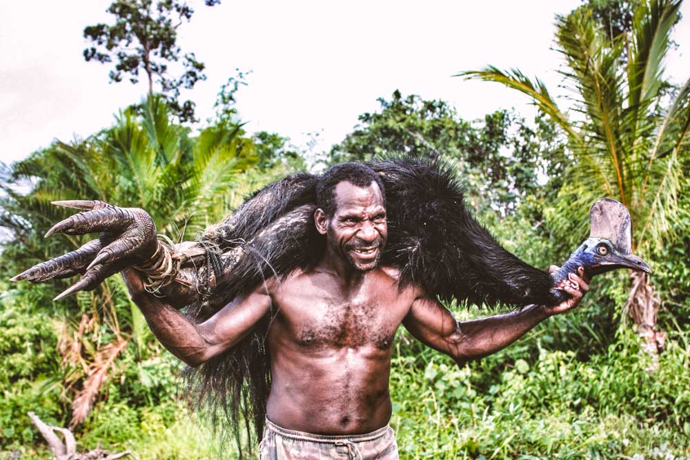 man carries cassowary on shoulder