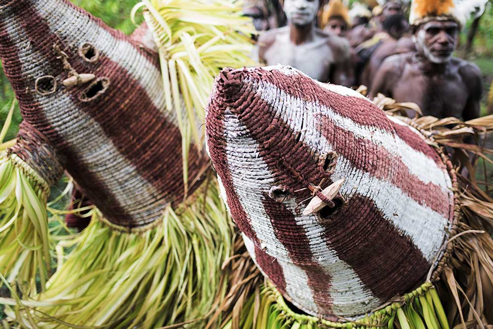 red-white striped dance masks with leaves and people in background