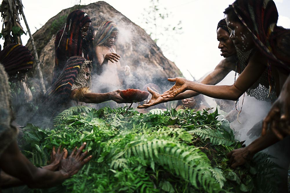 women hands reaching over cooking pit