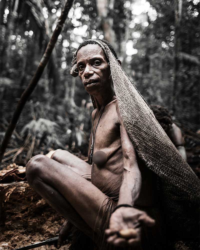 Korowai woman squatting presenting sago grub